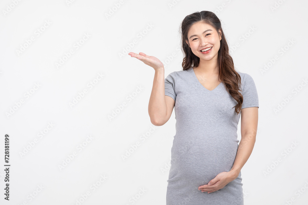 Happy Pregnant Woman standing smile stroking big belly with love and pointing on copy space isolated on white background,Pregnancy of young woman enjoy with future life,Motherhood and Pregnant Concept