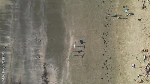 Group of surfers and their shadows walking down the beach