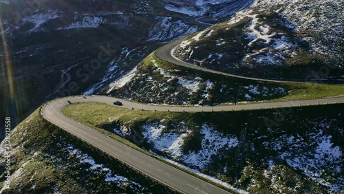 Serpentine mountain road. Aerial view of a sports car driving on beautiful twisty alpine road. Concept of a road trip and luxury travel. photo