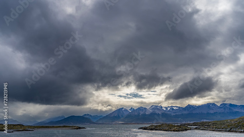 A picturesque mountain range of the Andes against a cloudy sky. In the foreground is the Beagle Channel with rocky islets. Argentina. Patagonia. Tierra del Fuego Archipelago