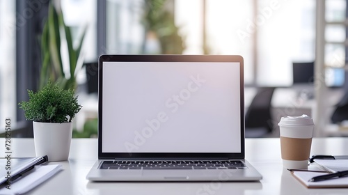 Laptop with blank screen on desk. isolated on blurred background. workbench with green plant and cup of coffe. for template, presentation. copy space. mockup. business concept.  photo