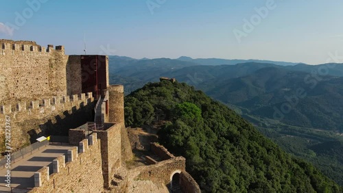 Montsoriu castle atop a lush hill in barcelona, spain, under clear skies, aerial view photo