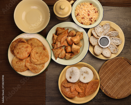 Bengali sweet savoury snacks variety stuffed pancake chitoi bhapa nakshi pakkon pitha singara samosa dal aloo puri fried flattened rice cheera mix on enamel tin metal plate over rustic background