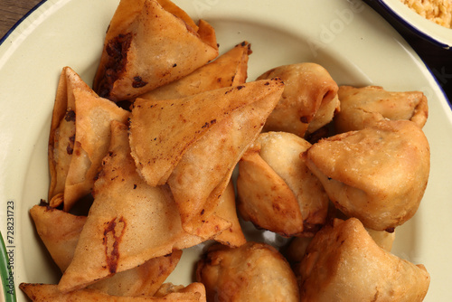 Deep fried samosa singara stuffed with potato minced meat vegetable benglai snacks on enamel tin metal plate photo