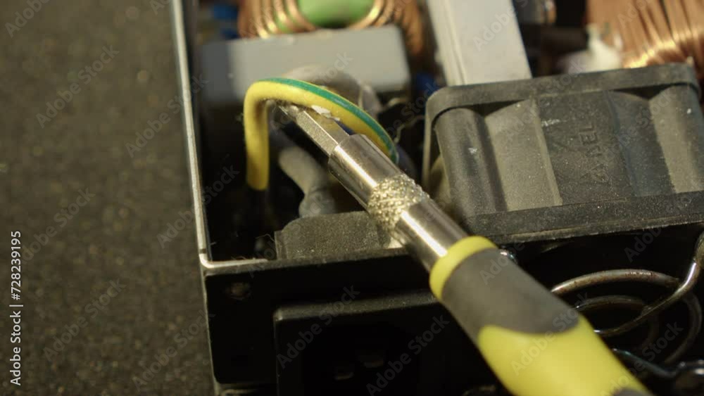 Workman uses screwdriver to remove wire from electronic power supply Workman uses screwdriver to remove wire from electronic power supply