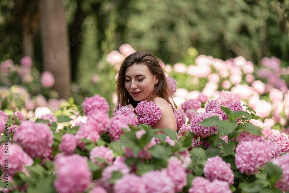 Hydrangeas Happy woman in pink dress amid hydrangeas. Large pink hydrangea caps surround woman. Sunny outdoor setting. Showcasing happy woman amid hydrangea bloom. Hydrangeas Happy woman in pink dress amid hydrangeas. Large pink hydrangea caps surround woman. Sunny outdoor setting. Showcasing happy woman amid hydrangea bloom.
