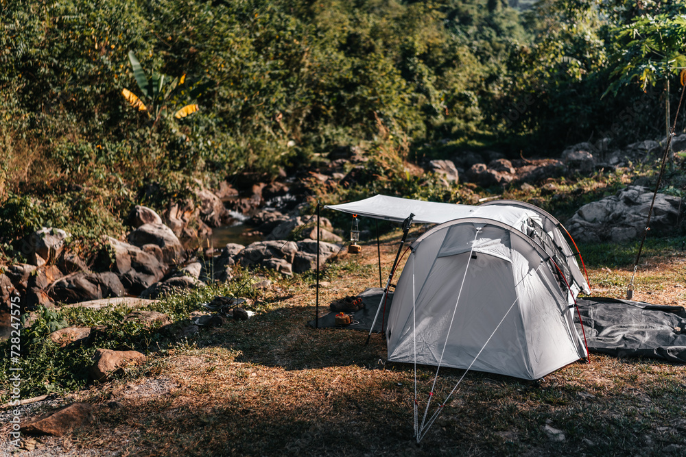 tents pitched on hillsides beside streams of water from waterfalls. canned gas with stove, hiking shoes, trekking pole on the ground. tents pitched on hillsides beside streams of water from waterfalls. canned gas with stove, hiking shoes, trekking pole on the ground.