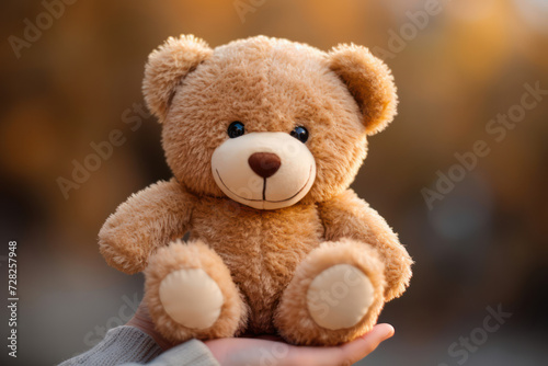  Close-up photo of a fluffy teddy bear in the tiny hands of a toddler against a soft-focus background