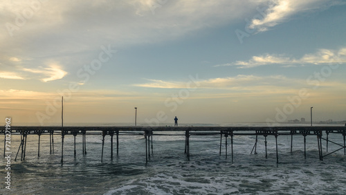 Lonely man standing on a pier at sunset. Feeling of peace or sadness. © Cavan