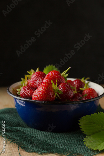 Sweet juicy strawberries in a blue metal vintage bowl