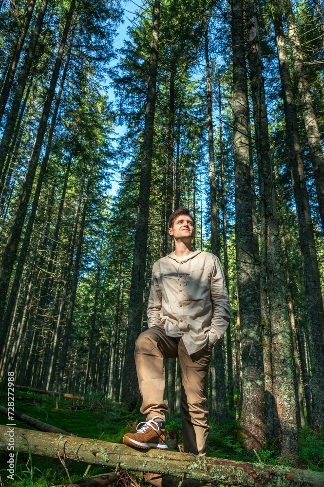 Young Male Hiker Looking Away While Standing Against Trees in Forest