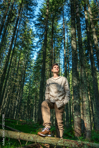 Young Male Hiker Looking Away While Standing Against Trees in Forest