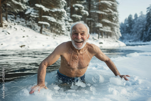 happy elderly gray-haired man bathes in an icy river in winter against the backdrop of a snowy forest
