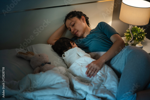 mother is breastfeeding a infant baby while lying and sleeping on bed at night photo