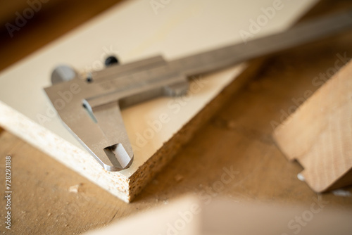 Close-up of a caliper lying on a table in a carpenter's workshop