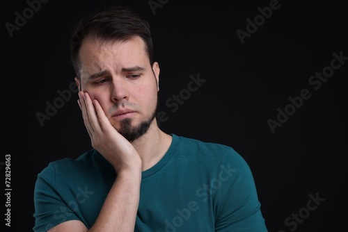 Portrait of sad man on black background, space for text