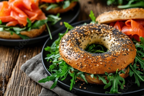 High angle view of a poppy seeds bagel spread with cheese cream and with smoked salmon and arugula topping on a rustic wooden table. 