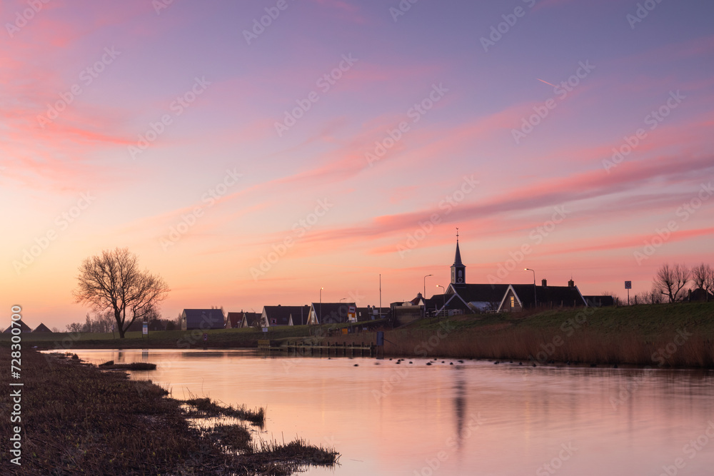 View of Oudesluis (North Holland) under a pastel-colored sky. Oudesluis, a small village in North Holland, is waking up.