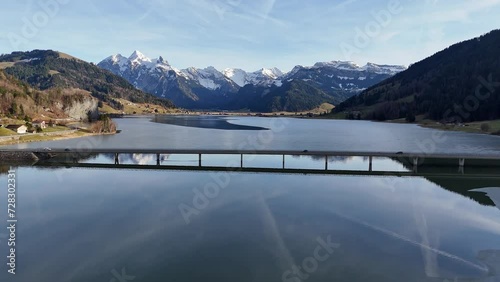 Tranquil Lake Sihl with Steinbach viaduct in Euthal, snow-capped mountains backdrop, clear reflection in water, peaceful Swiss landscape, aerial view photo