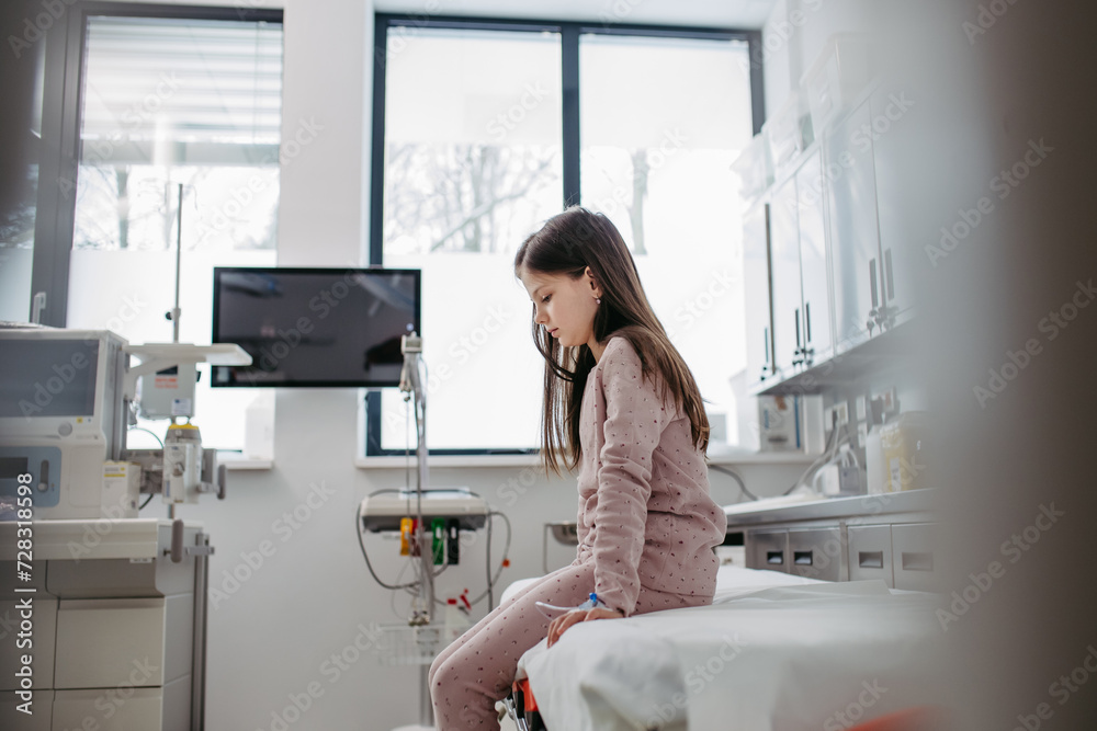 Worried children patient in emergency room, sitting on bed, waiting. Concept of emotional support and friendliness for young kid patient. Worried children patient in emergency room, sitting on bed, waiting. Concept of emotional support and friendliness for young kid patient.