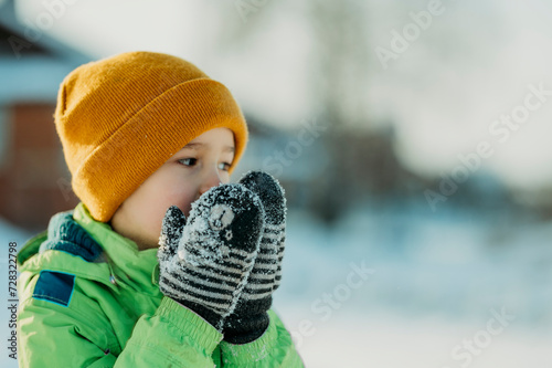 Boy wearing mitten and warming hands in winter