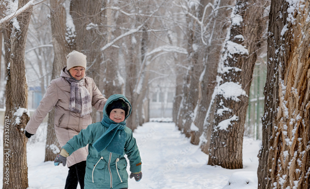 Happy senior woman playing with grandson at park in winter Happy senior woman playing with grandson at park in winter