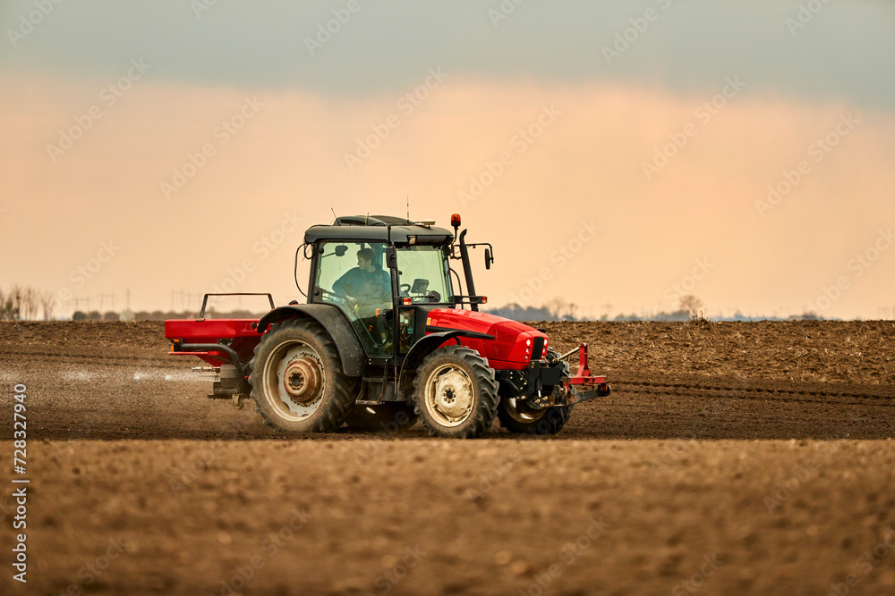 Farmer in tractor preparing field for cultivation at sunset Farmer in tractor preparing field for cultivation at sunset