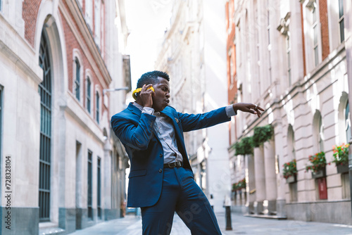 Businessman wearing wireless headphones and dancing on street photo