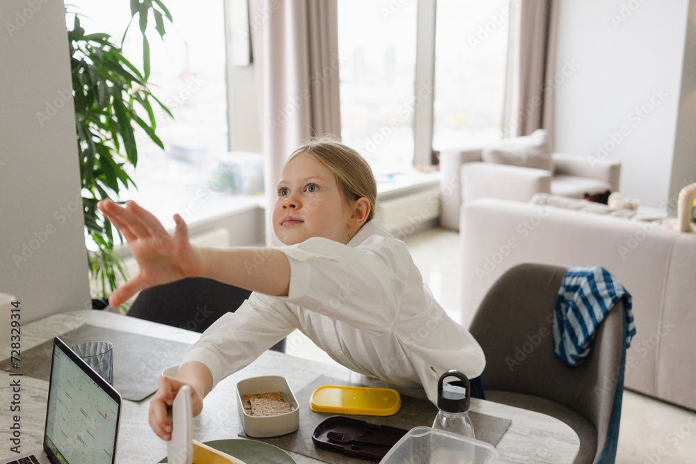 Girl packing lunch box at dining table Girl packing lunch box at dining table