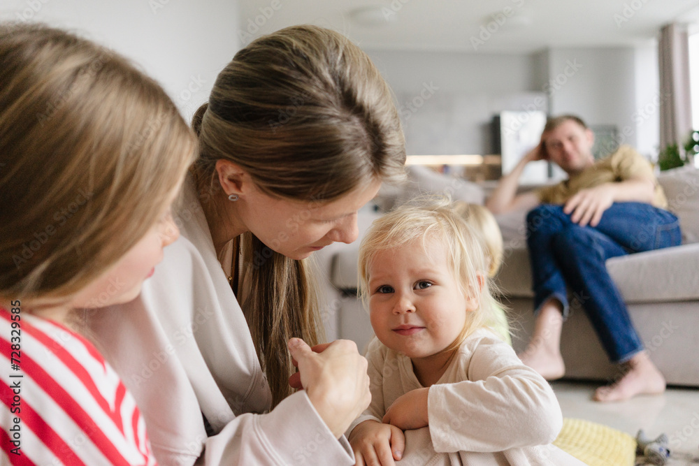 Mother consoling daughter with father in background at home Mother consoling daughter with father in background at home