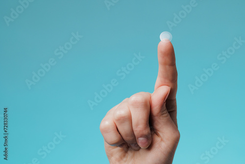 Εκτύπωση καμβά Close-up round acne patch on finger on blue background