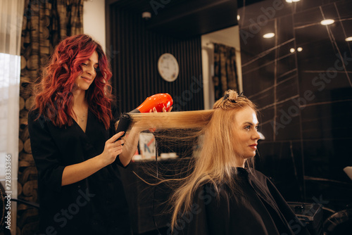 Beautiful woman at the hairdresser blow drying her hair