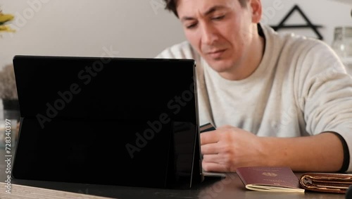 Disappointed man looking at his laptop with credit card in hand