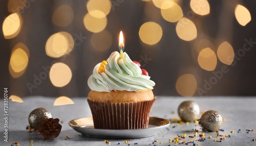 delicious birthday cupcake with burning candles on grey table against blurred lights
