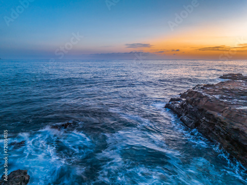 Fototapeta Naklejka Na Ścianę i Meble -  Sunrise over the calm ocean with light cloud and rocks