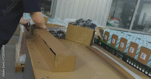 A woman packer packs a product into a box. Packing the goods in a box. Packer work in a factory photo