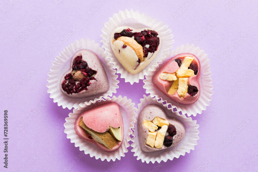 chocolate sweets in the form of a heart with fruits and nuts on a colored background. top view with space for text, holiday concept chocolate sweets in the form of a heart with fruits and nuts on a colored background. top view with space for text, holiday concept