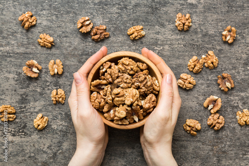 Woman hands holding a wooden bowl with walnut nuts. Healthy food and snack. Vegetarian snacks of different nuts