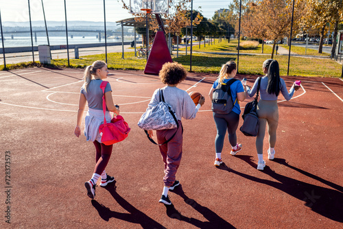 Diverse group of young woman walking on basketball court preparing to play.