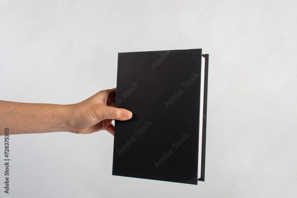 Blank black book cover in hand on white background. Blank black book cover in hand on white background.
