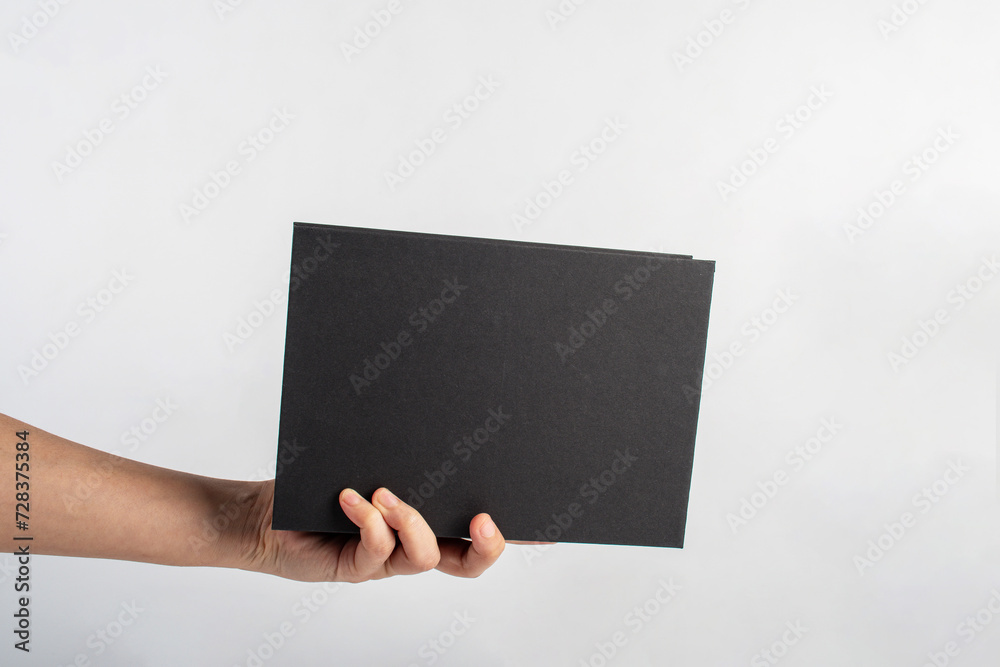 Blank black book cover in hand on white background. Blank black book cover in hand on white background.