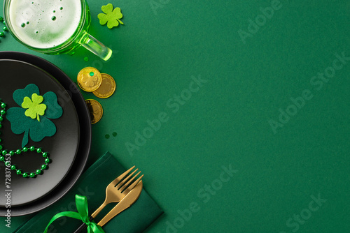 Celebrate in style at the pub for St. Patrick's: top view black plate, napkin holding knife and fork, beer glass, gold coins, trefoils, confetti, and beads displayed on a vivid green setting