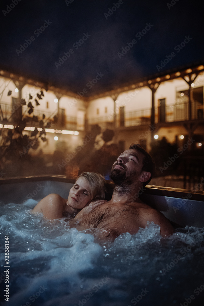 Beautiful mature couple relaxing in outdoor hot tub, enjoying romantic wellness weekend in spa. Concept of Valentine's Day.