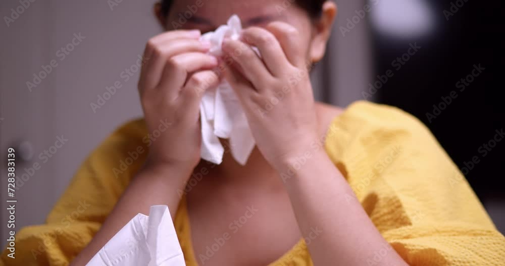 A crying, sorrowful woman is covering her face and wiping off the tears from her eyes as she continues to sob in despair.