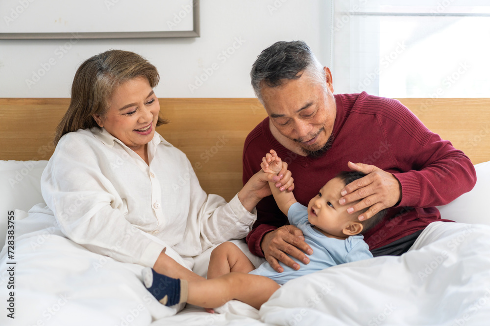 Portrait of happy love asian grandfather with grandmother playing with asian baby on bed, senior, insurance.Big family love with their laughing grandparents smiling together.Family and togetherness Portrait of happy love asian grandfather with grandmother playing with asian baby on bed, senior, insurance.Big family love with their laughing grandparents smiling together.Family and togetherness