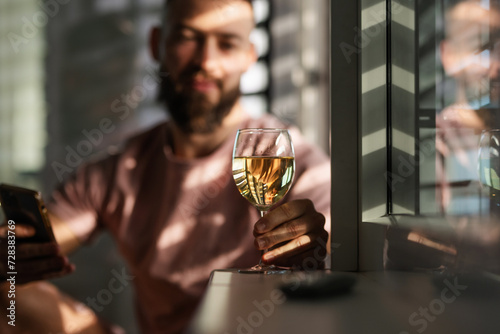 Young man looking at glass with white wine, New Year's resolutions, drink less alcohol healthy lifestyle without alcoholic drinks.