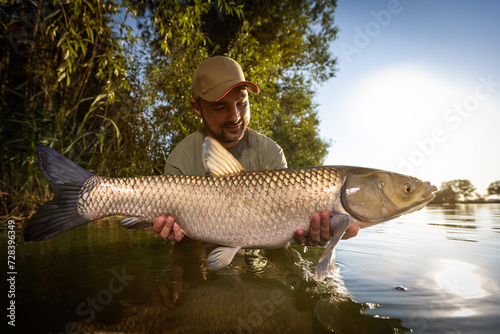 Fishing background. Young man hold big carp in his hands. 