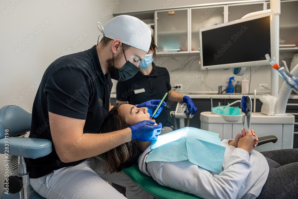 Obraz premium young girl laughs at a dentist examination with an assistant in a dental clinic.