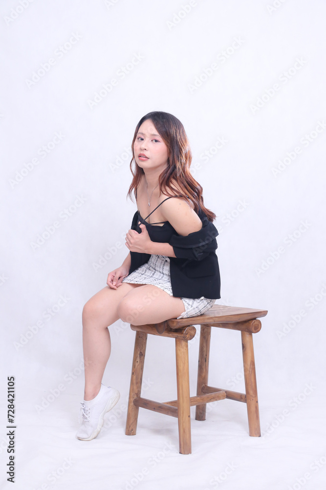 full body beautiful asian woman 20s formal office elegant sexy sitting sensual hands holding strap top pliers on wooden chair isolated white background full body beautiful asian woman 20s formal office elegant sexy sitting sensual hands holding strap top pliers on wooden chair isolated white background