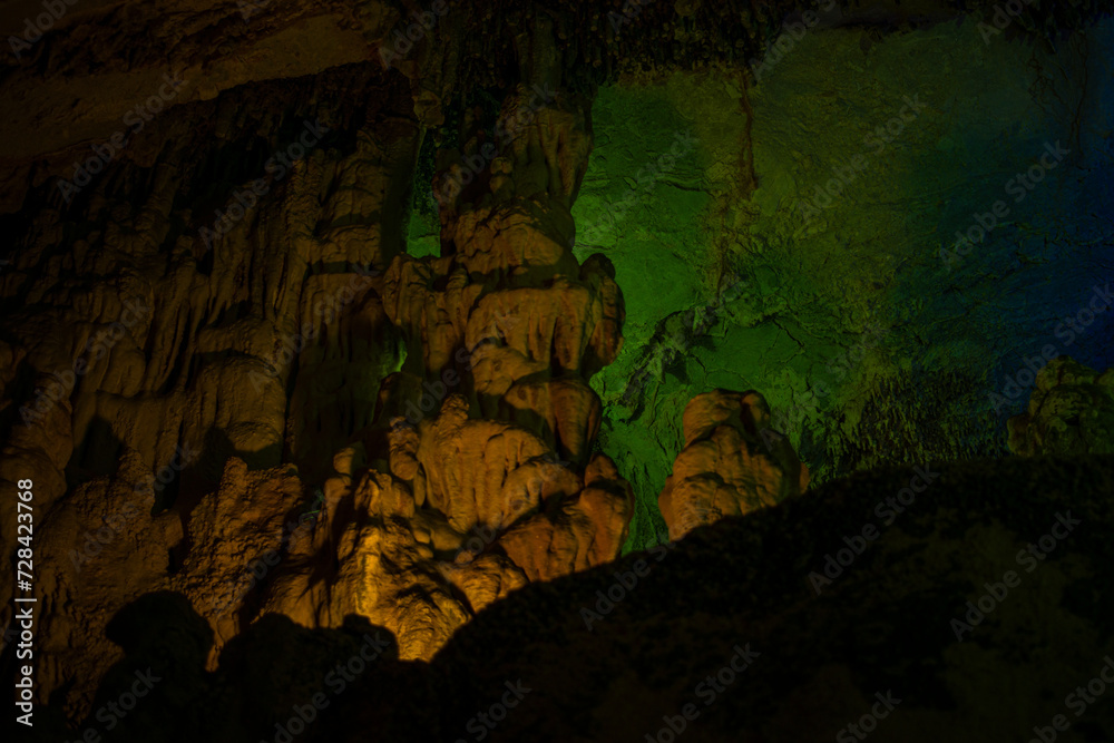 Journey through a vibrant cave adorned with colorful walls, stalactites, and stalagmites, revealing the underground beauty of nature's geological wonders.